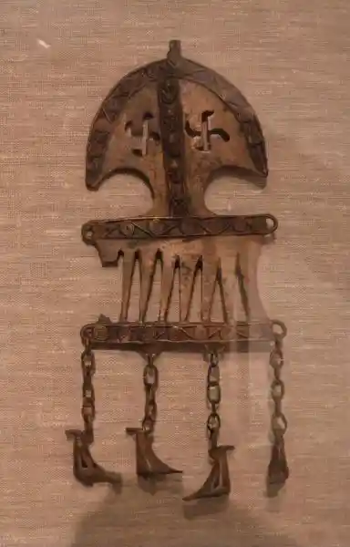 A prechristian pendant with a rounded swastika design - a cross with curved arms